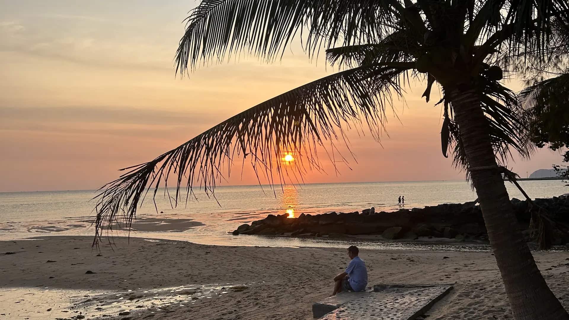 Fin de journée sur la côte ouest de Phuket, le soleil bas derrière les palmes et la mer d'Andaman