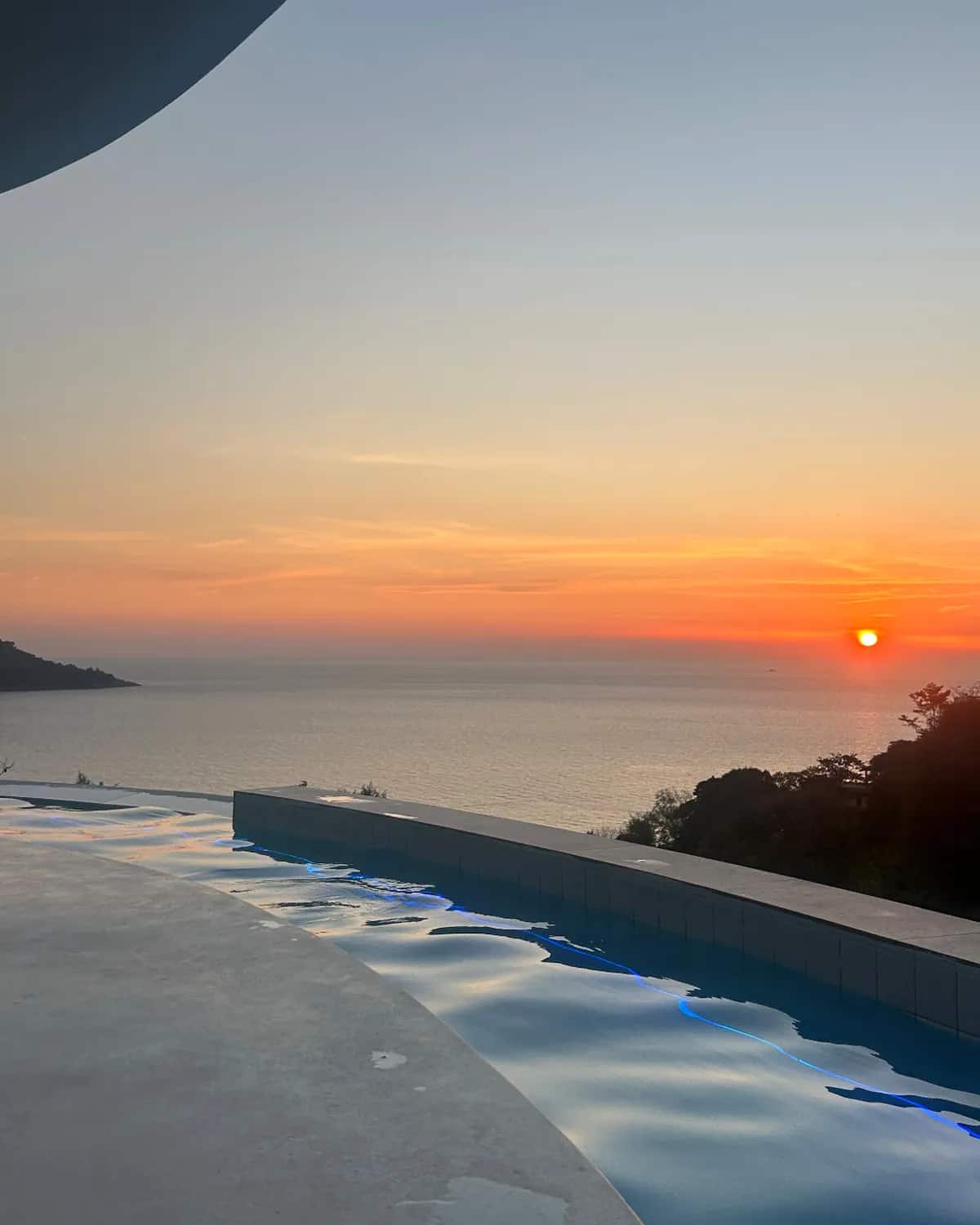 Piscine à débordement au-dessus d'une baie de Phuket, à la tombée du jour