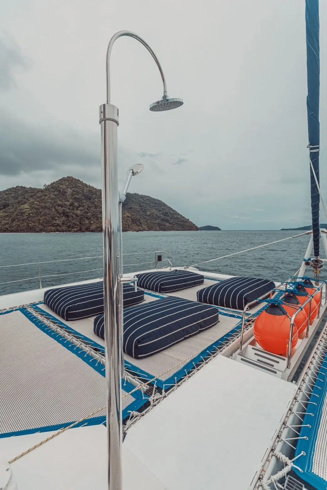 Pont avant d'un catamaran au mouillage face à une île boisée, au large de Phuket