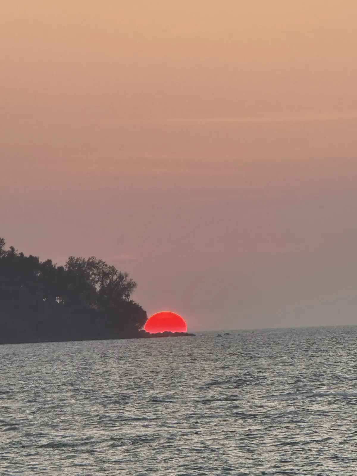 Soleil rouge descendant sur la mer d'Andaman, la côte boisée de Phuket en ombre chinoise