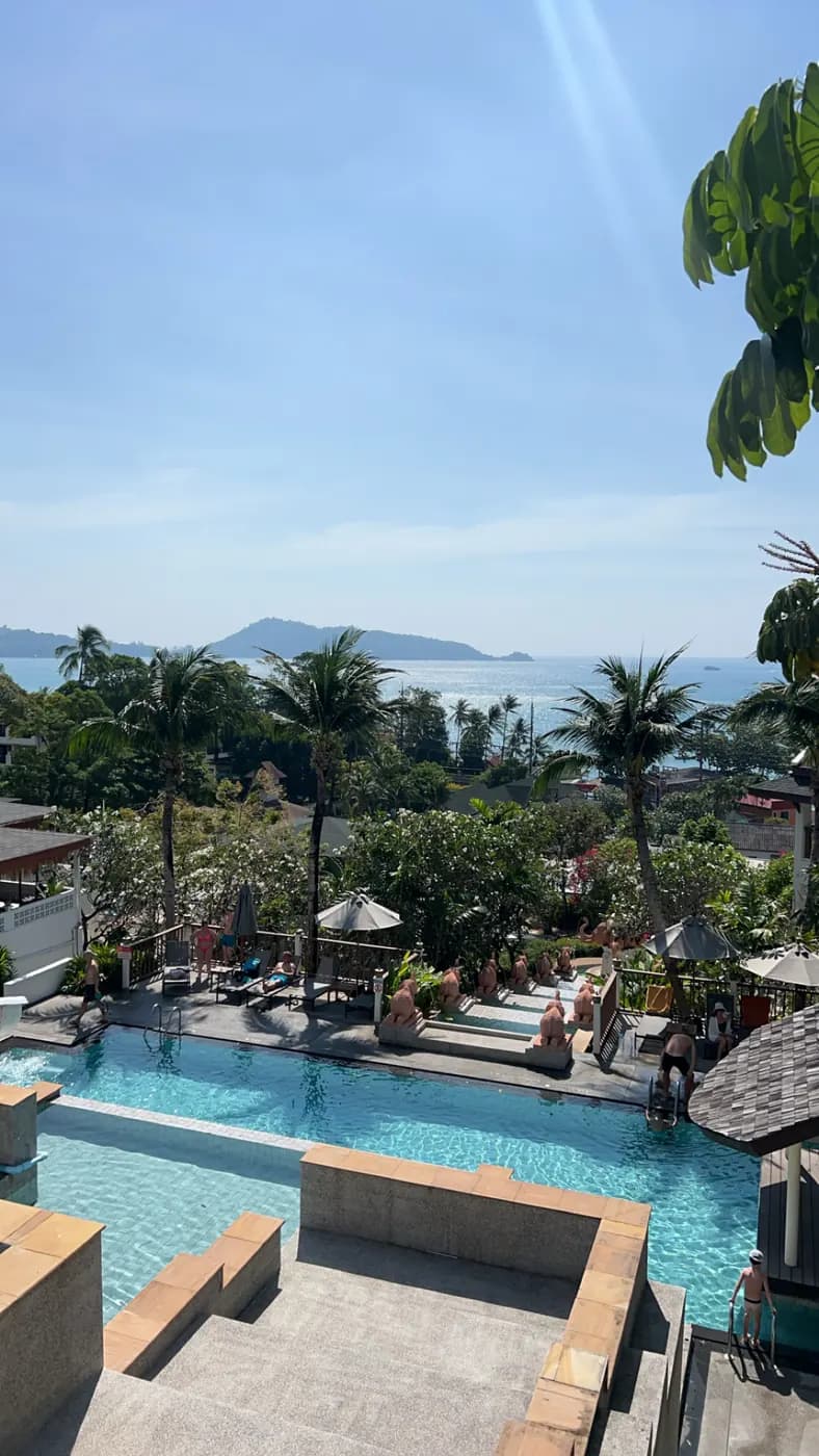 Piscine en terrasses d'un hôtel sur les hauteurs de Kalim, avec la baie de Patong et ses collines en arrière-plan