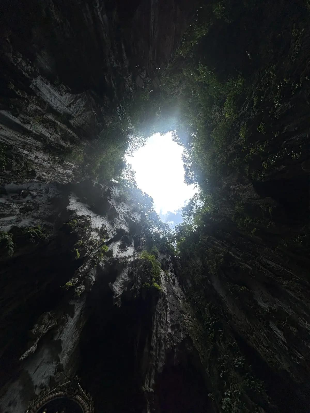 Ouverture de lumière au plafond d'une grotte calcaire, la roche humide éclairée depuis le haut