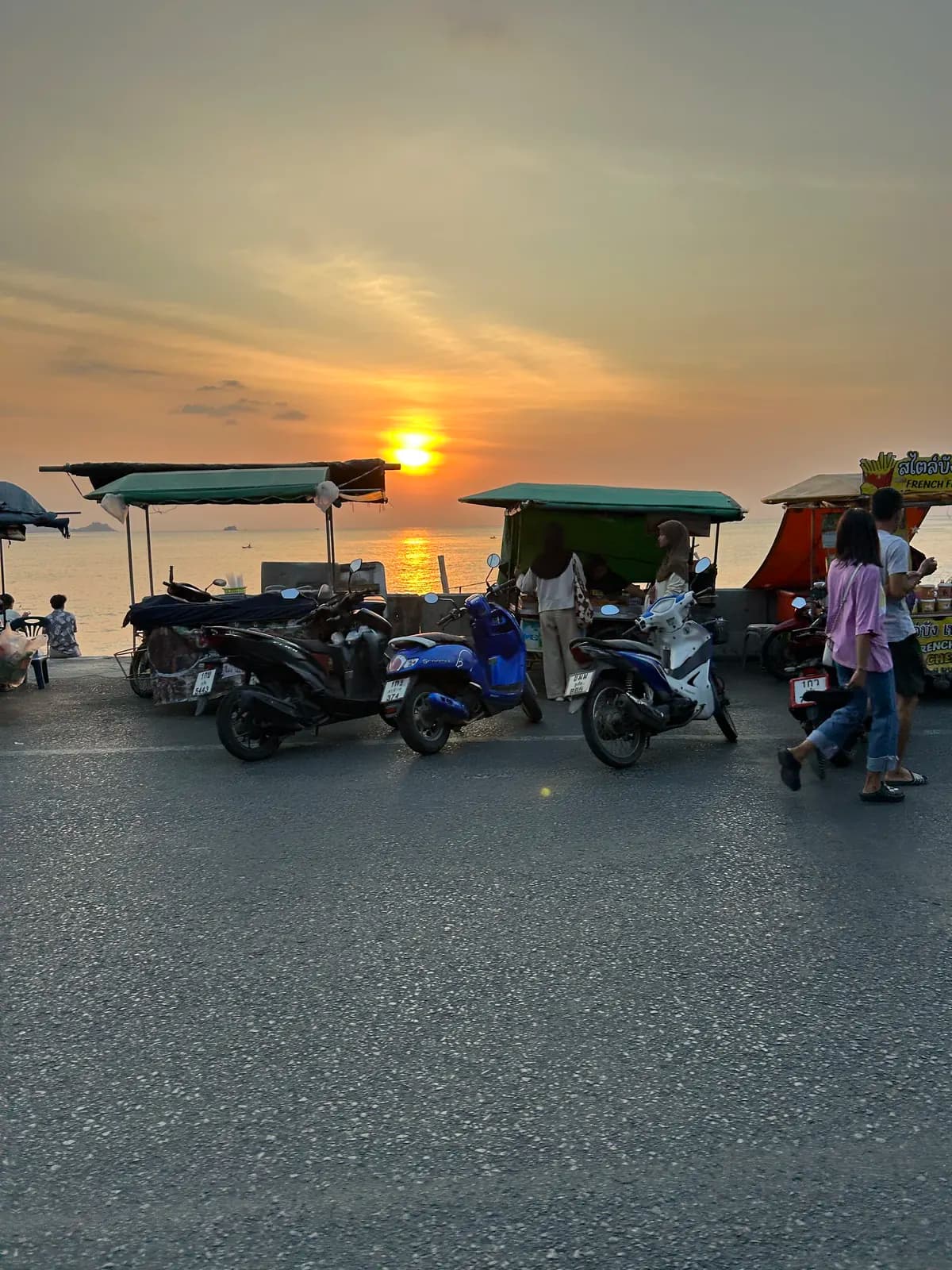 Stands de nourriture et scooters garés face à la mer, au coucher du soleil, à Patong