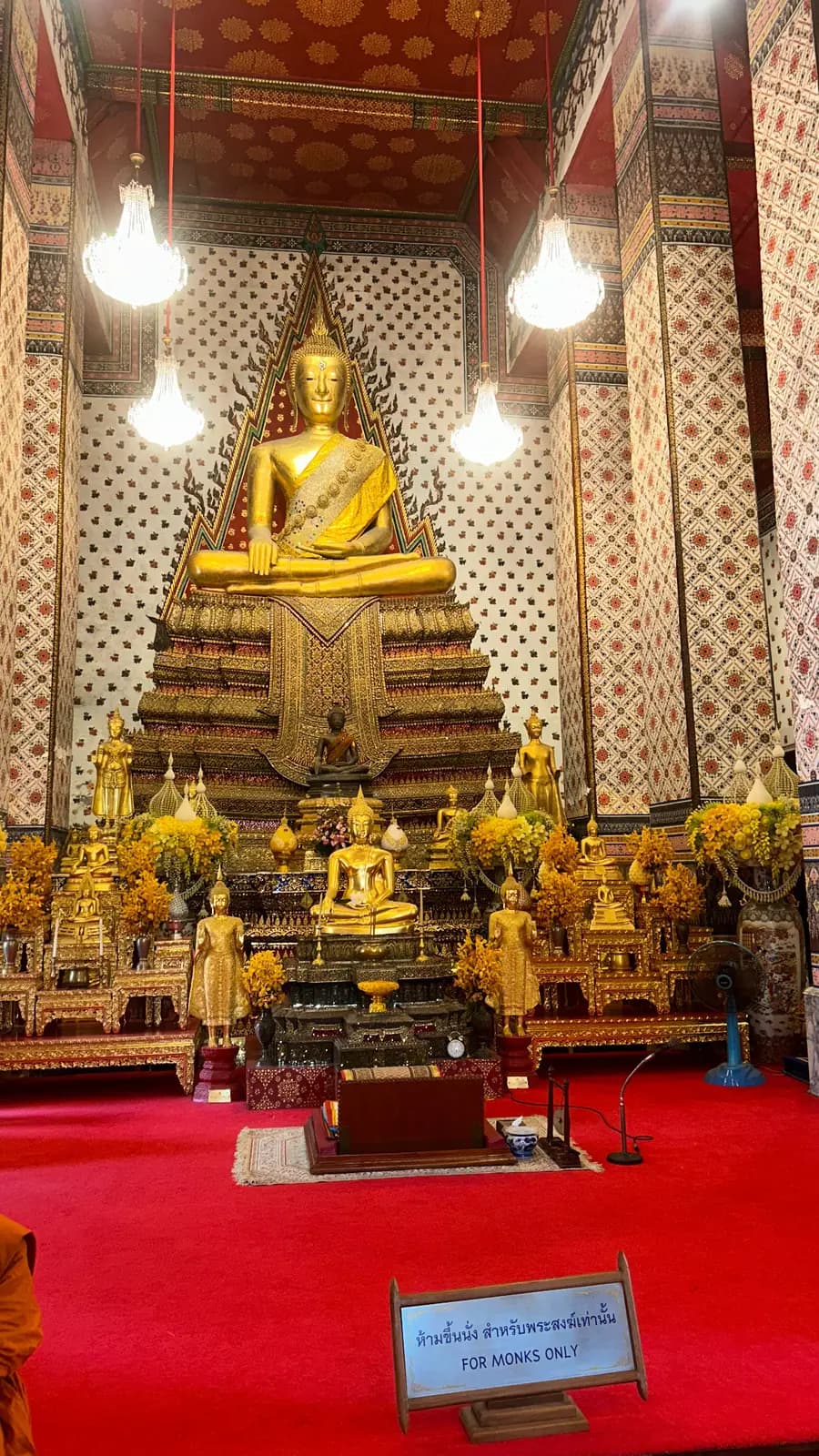 Bouddha doré assis dans le hall d'un temple bouddhiste de Thaïlande, entouré de colonnes ornées