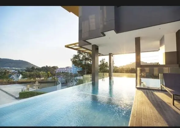 Infinity pool of a contemporary villa, wooden deck, hills in the evening light
